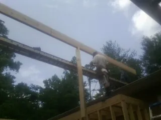 Carpenter setting a ridge beam over a new addition frame — Ice Dam Removal by Roofing Brothers in Manchester Center