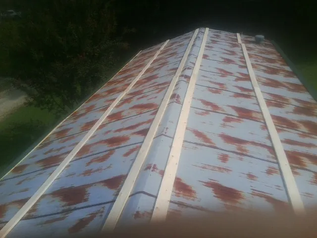Rusted metal roof panels with new wood purlins before replacement — Storm Damage Roof Repair in Manchester Center by Roofing Brothers