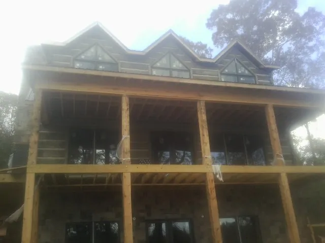 Dormers and porch framing on a large log home under construction — Roof Coating work by our crew in Manchester Center