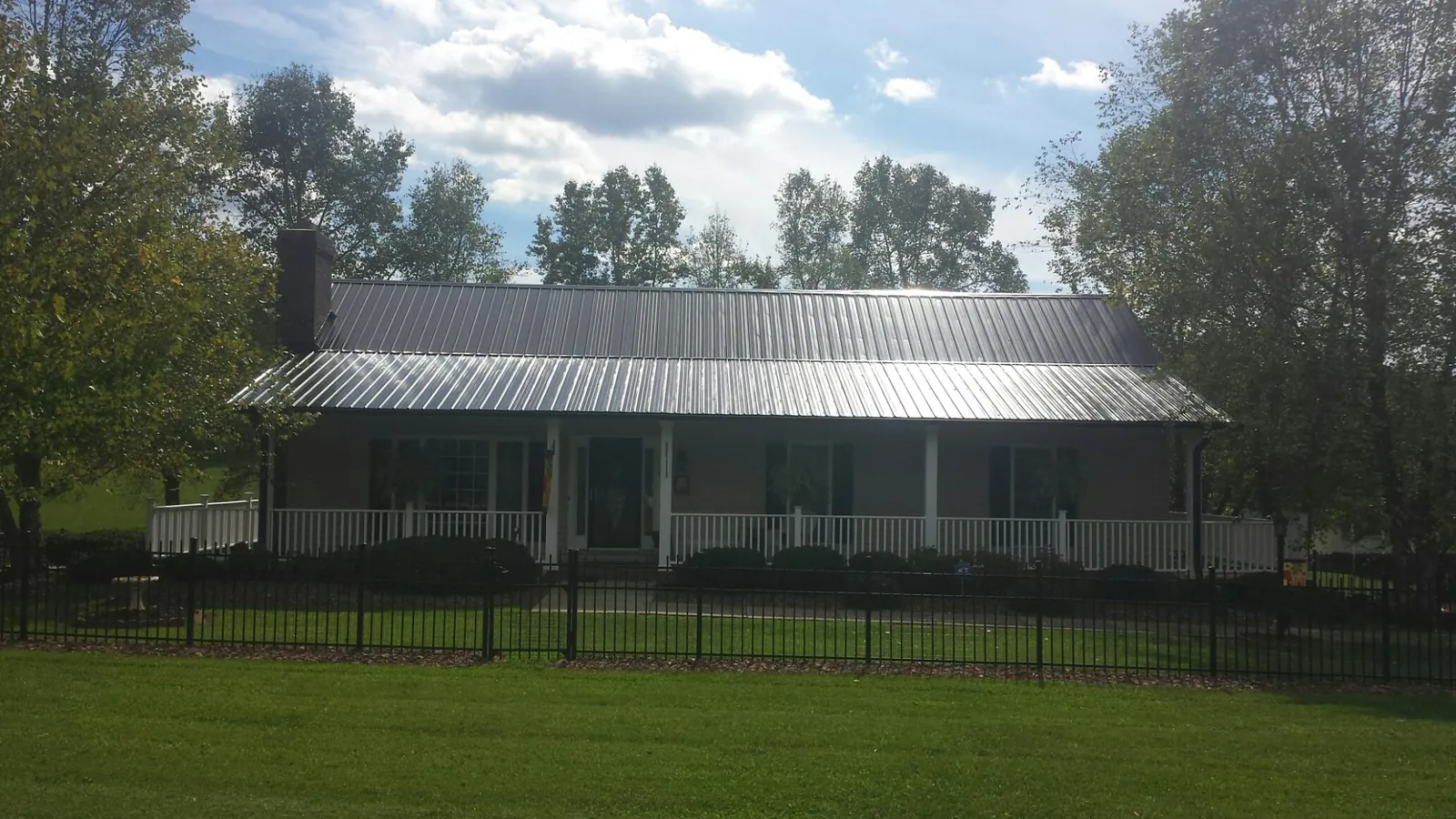 Gray metal roof on a brick ranch with a full width front porch — Gutter Guard Installation work by our crew in Manchester Center