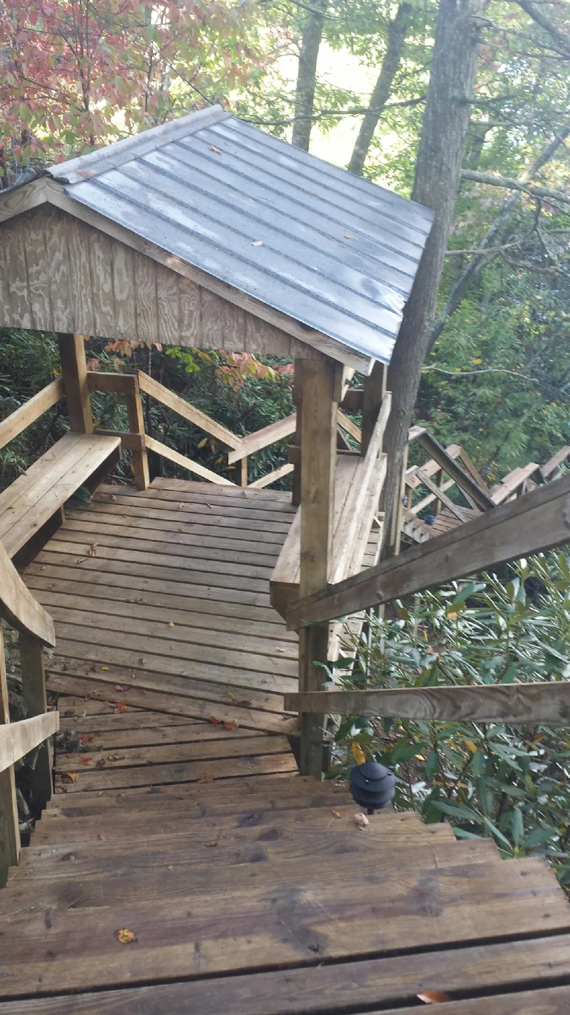 Metal roofed shelter over wooden steps on a wooded walkway — Skylight Repair & Installation work by our crew in Manchester Center