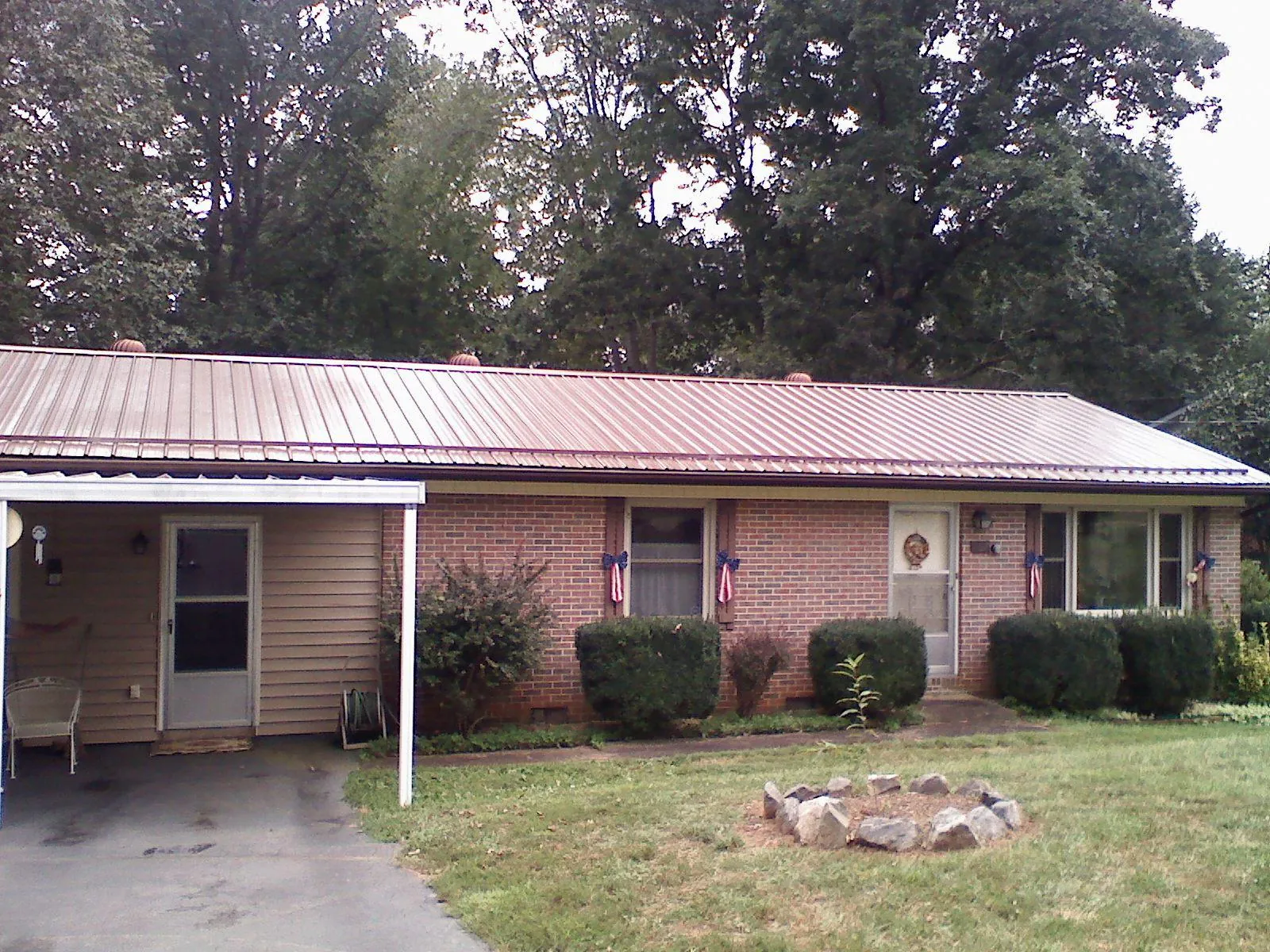 Bronze metal roof and carport on a brick ranch home — Roof Repair work by our crew in Manchester Center