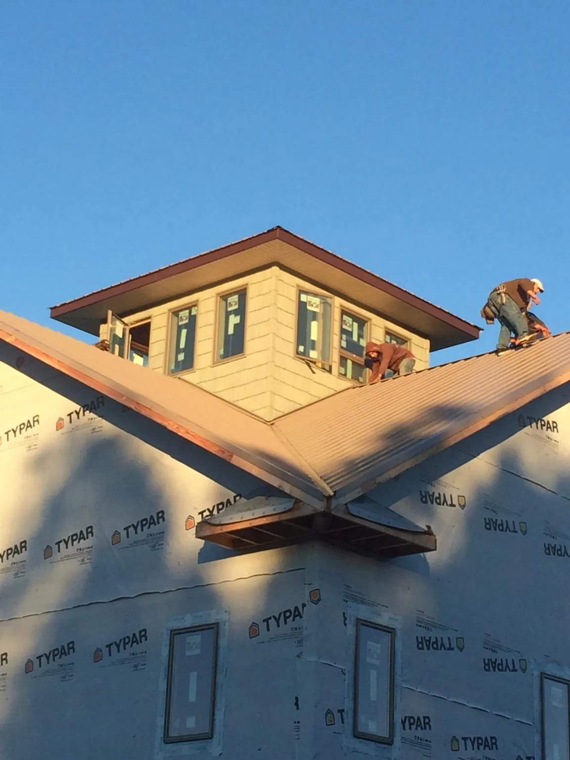 Roofers working around a rooftop cupola on a new metal roof at sunset — Roof Waterproofing in Manchester Center by Roofing Brothers